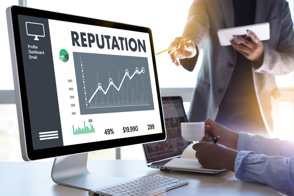 Painel com gráfico que indica crescimento de reputação digital.  Em volta do painel, há dois profissionais: um profissional segurando um lápis e um bloco de anotações e uma profissional segurando uma caneta e uma xícara. 