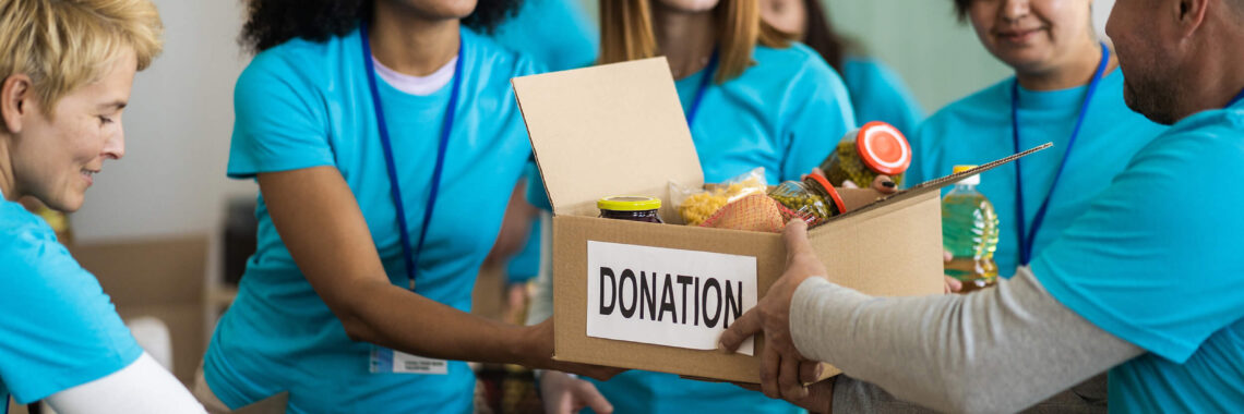 Voluntários de uma OSC segurando uma caixa de doação de alimentos.