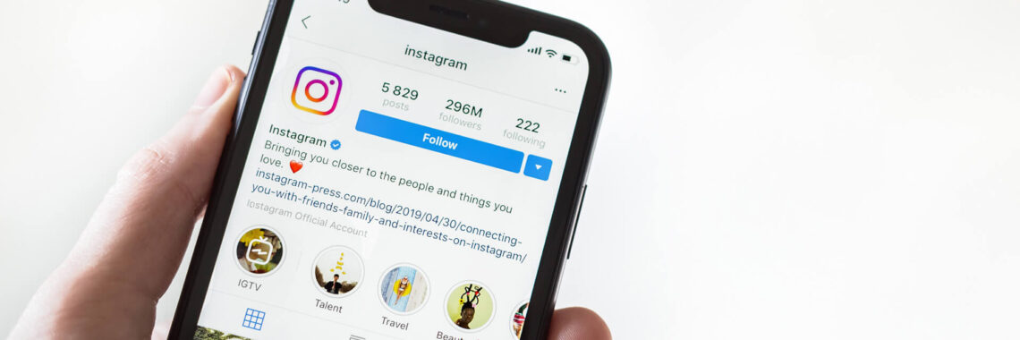 Mão segurando telefone com o aplicativo Instagram na tela.