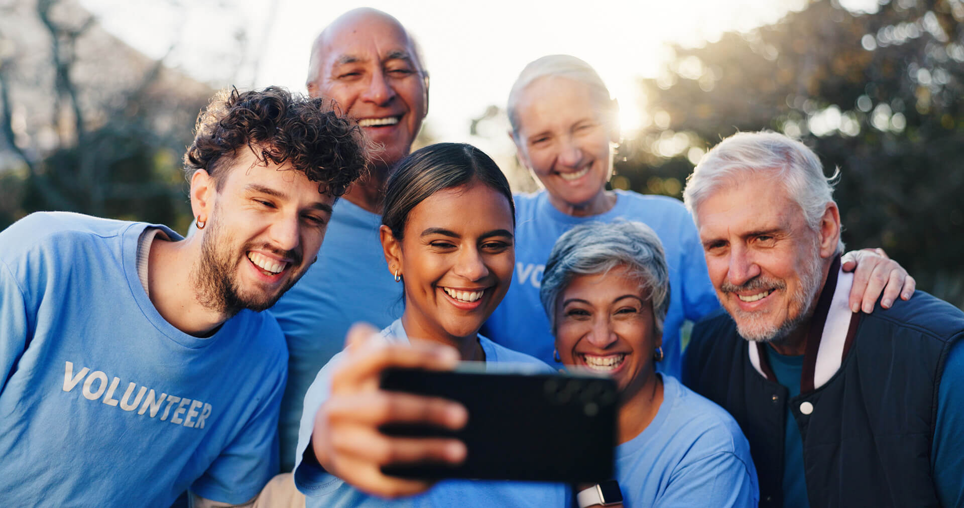 Grupo de voluntários tirando foto, representando trabalho em equipe e engajamento social.