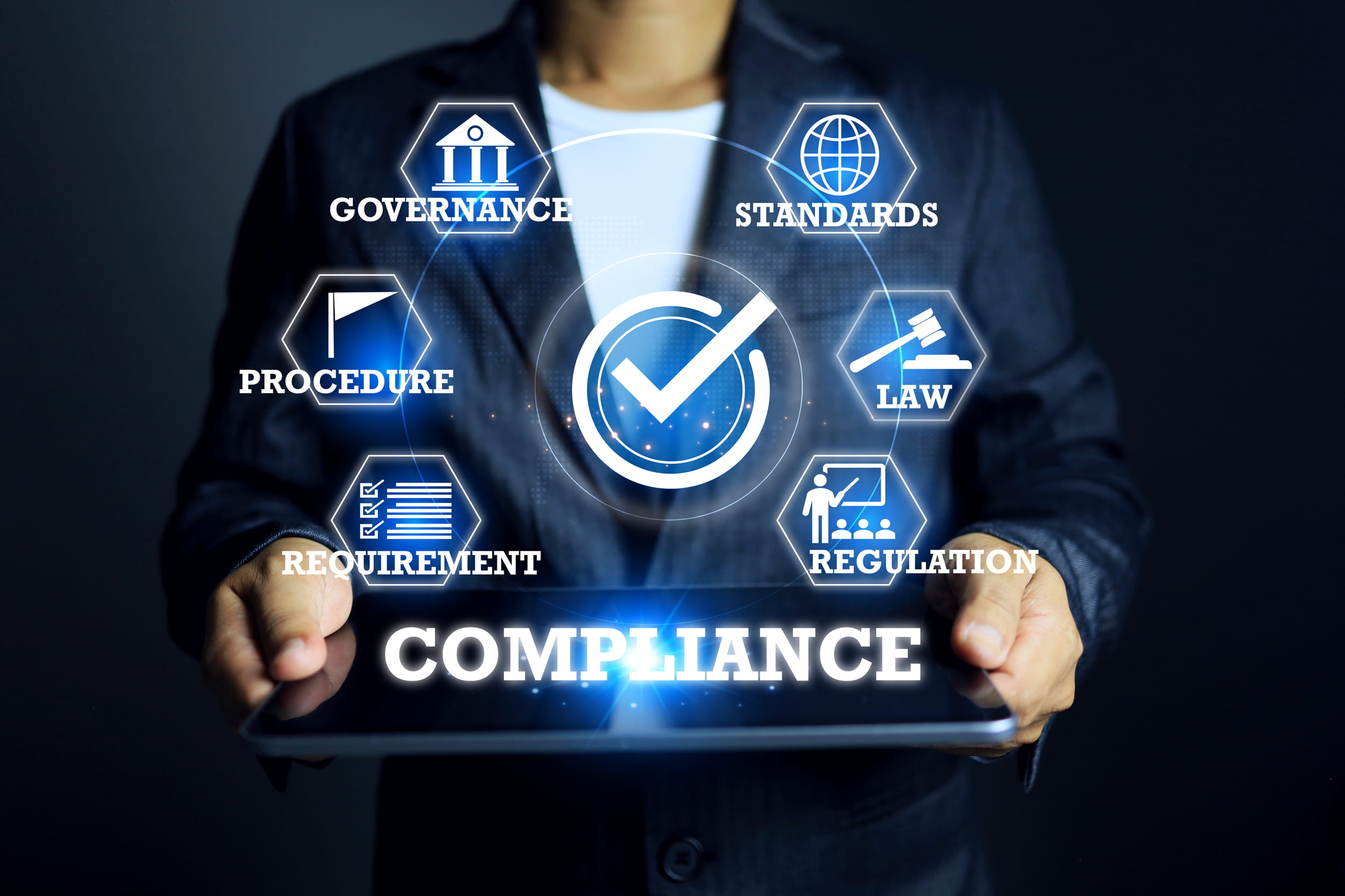 Profissional de camiseta e paletó segurando tablet com ícones digitais de conformidade: governança, normas, leis, procedimentos, requisitos e regulamentação.