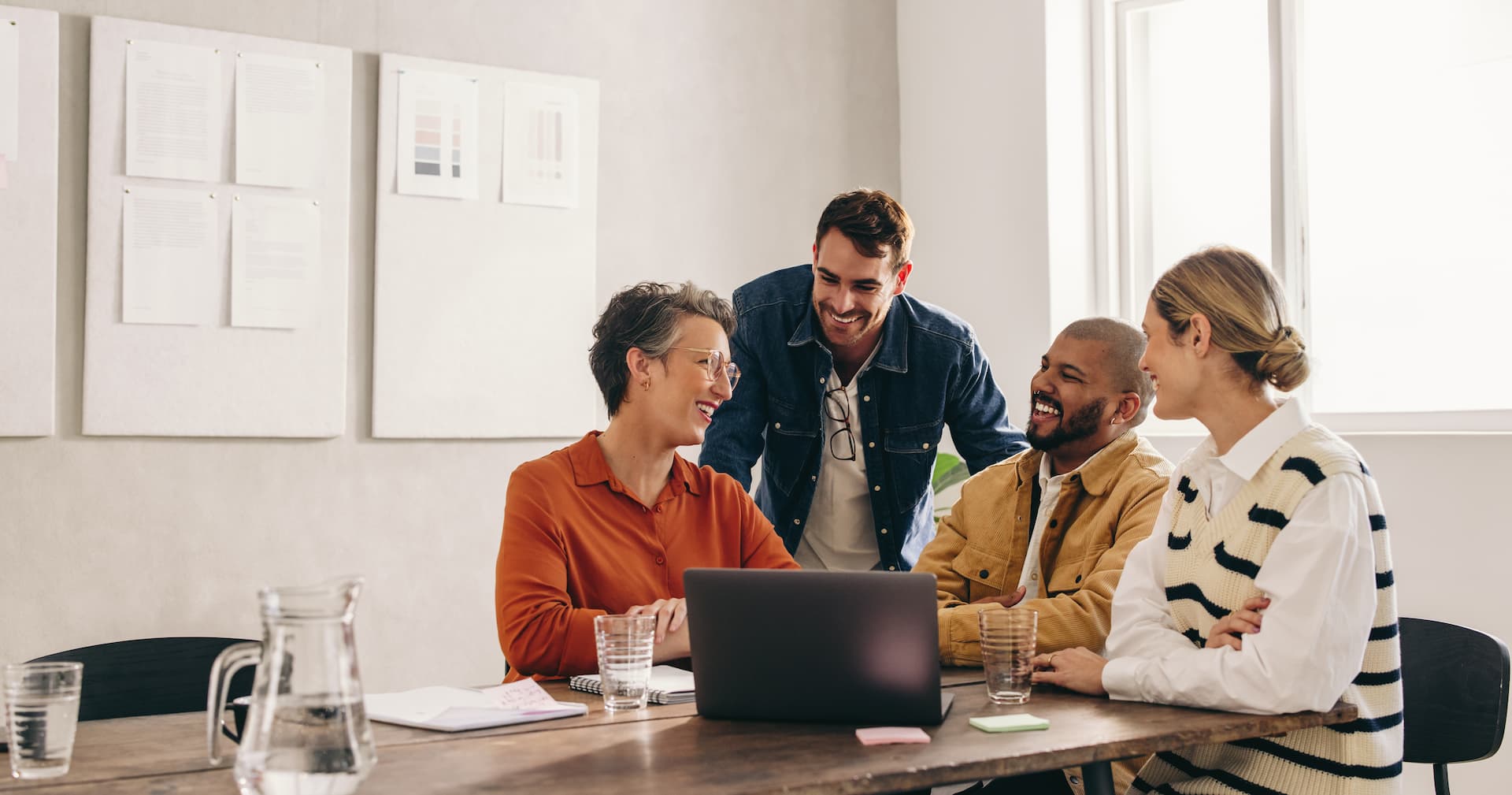 Quatro profissionais sorrindo em uma reunião, demonstrando felicidade no trabalho.