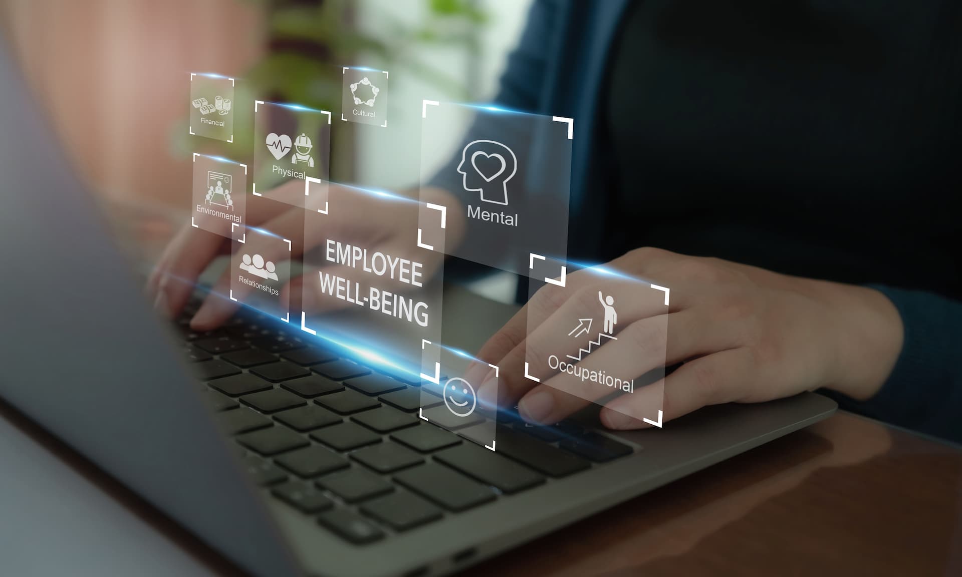 Profissional digitando em notebook com interface digital sobre bem-estar do colaborador, saúde mental, saúde física e riscos ocupacionais no ambiente de trabalho.
